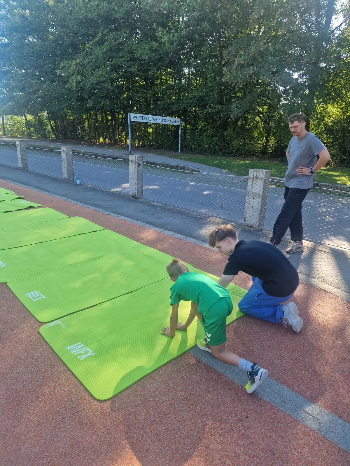 Teilnehmende bereiten sich beim Parcours-Training in Wuppertal auf grünen Matten vor